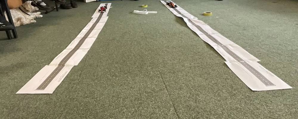Pupils racing remote-control cars on paper tracks